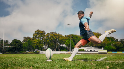 Rugby, action and man kicking ball to score goal on field at game, match or practice workout. Sports, fitness and motion, player running to kick at poles on grass with energy and skill in team sport. - Powered by Adobe