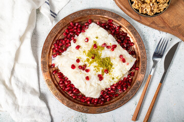 Gullac dessert. Ramadan dessert. Gullac decorated with pomegranate and pistachio in copper plate on gray background. Symbolic food