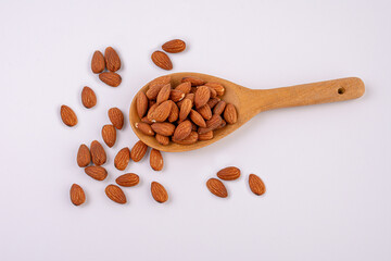 Almonds seed on wood spoon isolated on white background