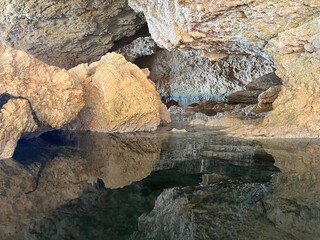 Cave cavern grotto rocks with reflections in water.