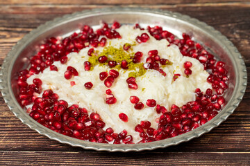 Gullac dessert. Ramadan dessert. Gullac decorated with pomegranate and pistachio on a copper plate on wood background. Symbolic food.