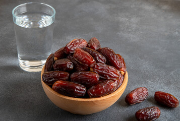 Glass of water with a bowl of date fruit on black background 