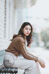 Fototapeta premium Beautiful Asian woman Smiling happy girl and wearing warm clothes winter and autumn portrait at outdoor sitting on bench.