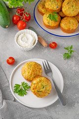 Homemade zucchini muffins with cheese, garlic and herbs on a plate on a gray concrete background. Vegetarian dish. Copy space.
