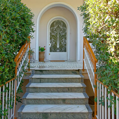 Corridor and stairs of an elegant house arched entrance and decorated white painted iron door. Travel to Athens, Greece.
