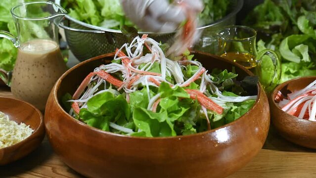 Hand chef sprinkle parmesan cheese shredded on caesar salad in wood blow. Caesar salad or green salad in wood blow must sprinkle by parmesan cheese shredded. parmesan cheese shredded is mix in Italian