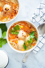 Potato balls soup with noodles and vegetables in white bowl, white background. Vegan food concept.