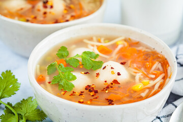 Potato balls soup with noodles and vegetables in white bowl, white background. Vegan food concept.