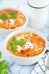 Potato balls soup with noodles and vegetables in white bowl, white background. Vegan food concept.