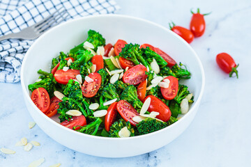 Broccoli salad with cherry tomatoes and almonds in white bowl. Vegan detox recipe.