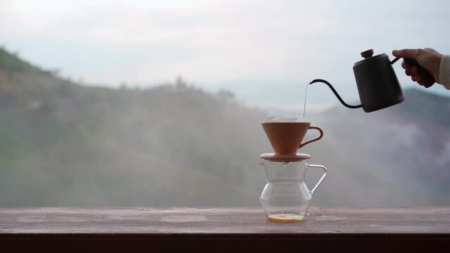 Drip coffee with beautiful mountains view and mist in the morning on wooden table