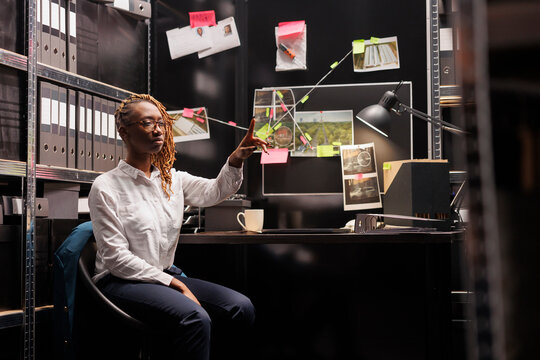 Private detective using augmented reality technology for clues analysis. African american woman investigator making hand gesture and pointing with finger while working in ar