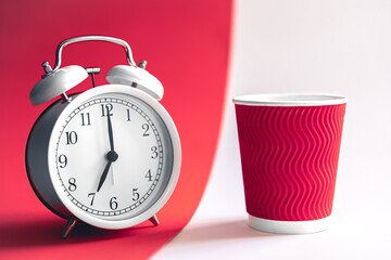 White stylish alarm clock and paper cup, morning concept.