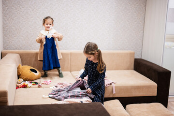 Two sisters are choosing clothes from the wardrobe at home on the sofa.
