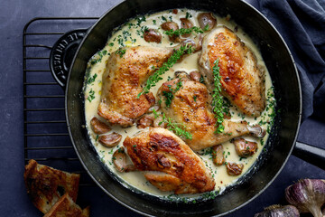 French style garlic chicken in a creamy sauce served in a black cast iron pan with wooden handle