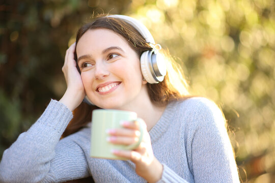Happy woman listening to music drinking coffee