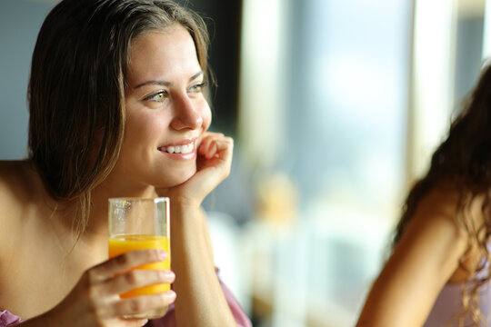 Happy woman holding orange juice glass at breakfast