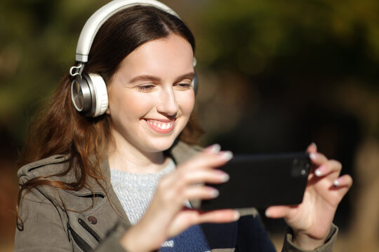 Happy woman watching and listening video on phone