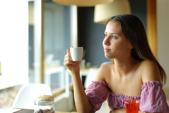 Woman looks away holding coffee in a restaurant