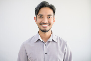 Portrait of a handsome Asian man with a beard in a gray shirt making a smile face. - obrazy, fototapety, plakaty