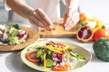 A woman makes a fresh vegetable salad, close-up.