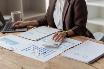 Close-up shot of businesswoman using calculator and laptop to calculate company financial result On...