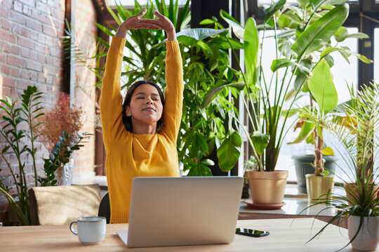 Tired businesswoman stretching arms after work at loft office