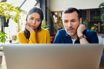 Focused business colleagues watching laptop at loft office