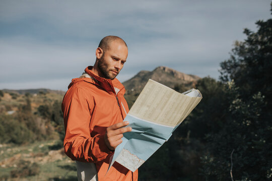Smiling man reading map standing in nature