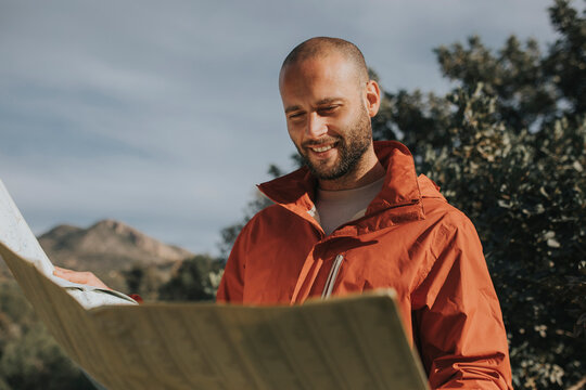 Smiling man reading map standing in nature