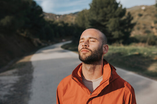 Sunlight falling on face of man standing on road with closed eyes