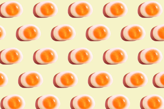 Pattern of egg shaped candy flat laid against yellow background
