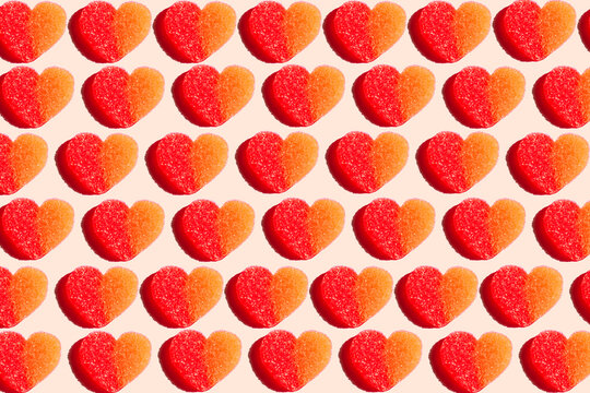 Pattern of heart shaped candy flat laid against yellow background