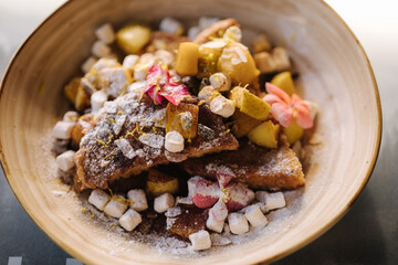 Top view of homemade french toast sticks with marshmallows, powdered sugar and caramelised pear