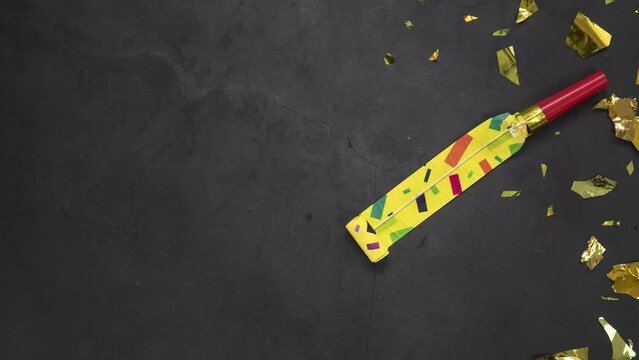 Birthday party blowouts whistles Rolled festive noisemaker or party whistle on concrete dark background, blowing in whistle top view in and out loop 4k Happy Birthday copy space