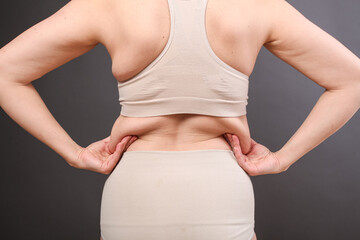 young woman in postpartum corrective tightening underwear shows her overweight. The girl squeezes...