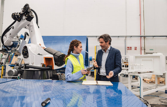 Engineers having discussions standing in robotics factory