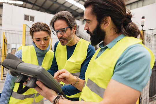 Engineers using controller in robotics factory