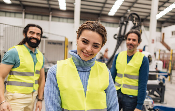 Happy engineers wearing reflective clothing standing with in robotics factory