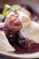 Macro photo of curd fritters in cream-berry sauce with bilberry. Cheesecake decorated sour cream and mint.