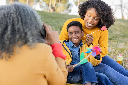 Woman talking photos of daughter and grandson sitting in park