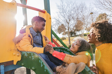 Boy having fun with family on slide on playground