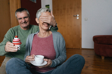 Happy senior couple sitting on the floor at home having fun