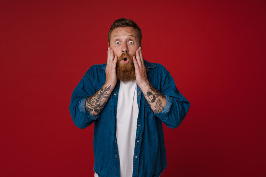 Adult bearded tattooed handsome shocked redhead man with opened mouth