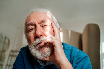 Thoughtful senior man with gray hair sitting at home