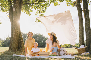 Happy women sitting with sons on picnic blanket in park