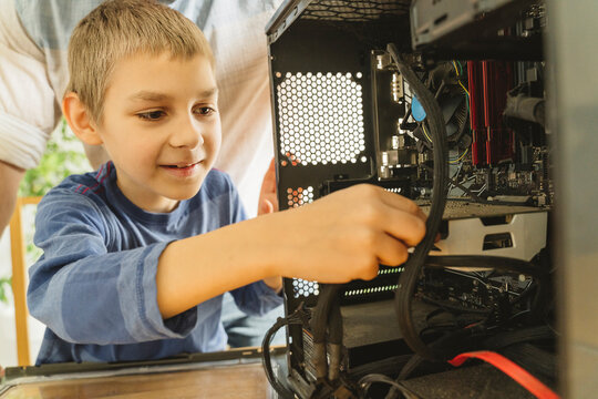 Smiling boy cleaning computer parts at home