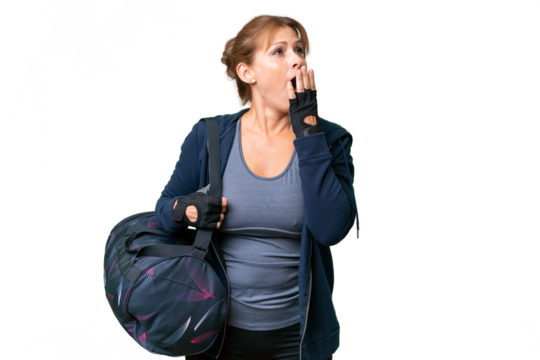 Middle-aged sport woman with sport bag over isolated background yawning and covering wide open mouth with hand