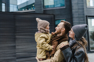 Happy mother and father with son standing in front of building