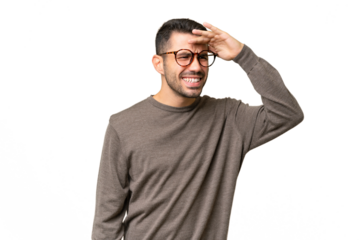 Young handsome caucasian man over isolated background looking far away with hand to look something